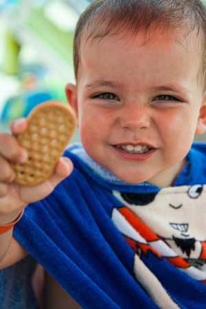 child with bathrobe with drawing pirate eating cookieの写真素材