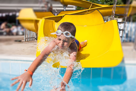 happy child playing with the slide in the poolの写真素材