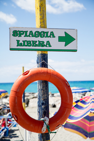 free beach, indicator sign on wooden post with orange lifesaverの写真素材