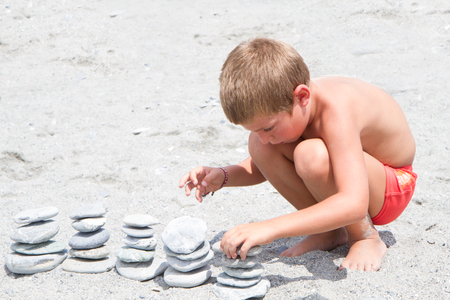 child playing on the beach, pile of stonesの写真素材
