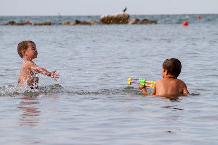 Happy childs play into sea with watergun, vacation in Italy Cesenaticoの写真素材