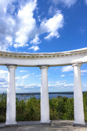 White doric columns against bushes river and blue sky with cloudsの写真素材