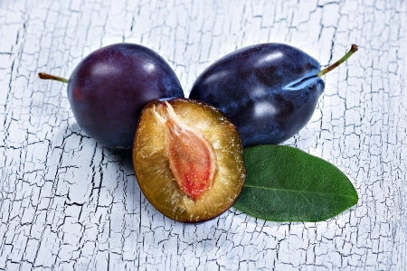 two plums and a halved fruitの写真素材