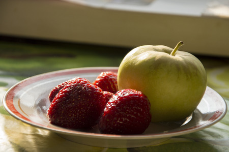 Apple and strawberry on a saucerの写真素材