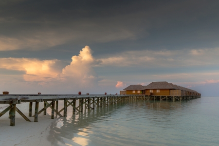 Maldives beach villas in sunset scenery with strong cloud formationのeditorial素材