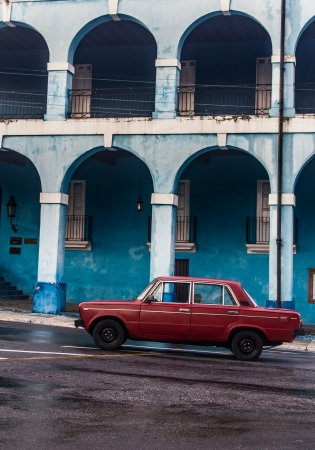 Picture of red old car in front of blue buildingの写真素材