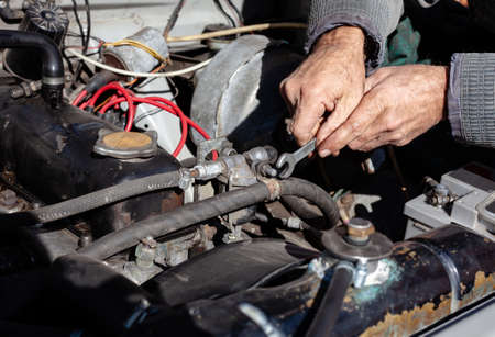 the mechanic uses a wrench to connect the hose. DIY repair. troubleshooting process. under the hood workingの写真素材