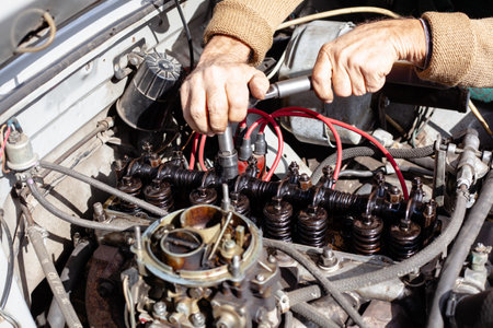 the mechanic uses a torque wrench to repair gas distribution mechanism at old engine. Disassembled carburetor motor. DIY repair. cylinder head with camshaftの写真素材