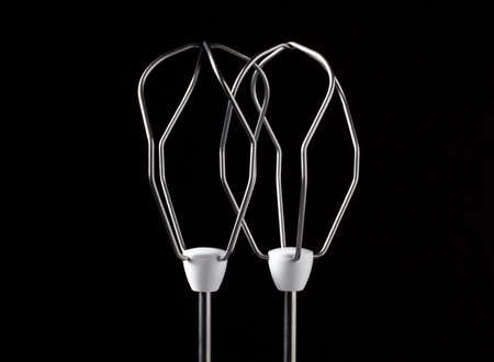 Two stirring dough and beating eggs whisks in working position a part of hand mixer photographed against dark backgroundの写真素材