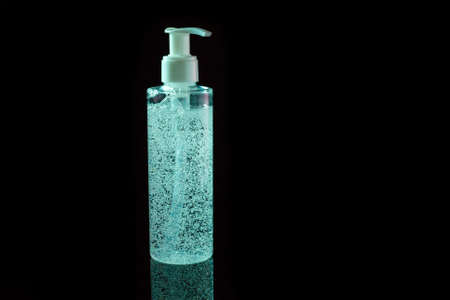 Cosmetic product for makeup remove. Cyan liquid with small air bubbles. Bottle with dispenser. On dark surface background.の写真素材