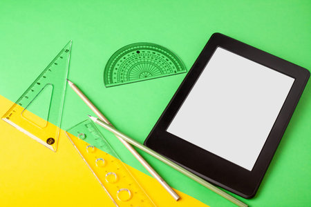 School office supplies and electronic book reader with blank screen for copy space on a color...