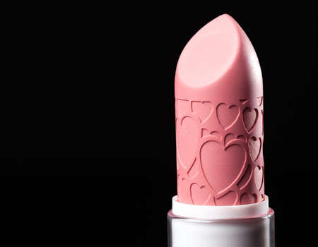 Close-up pink lipstick with heart prints design isolated on black background. Close up. Macro. Detailed photo of make up product. Lip stickの写真素材