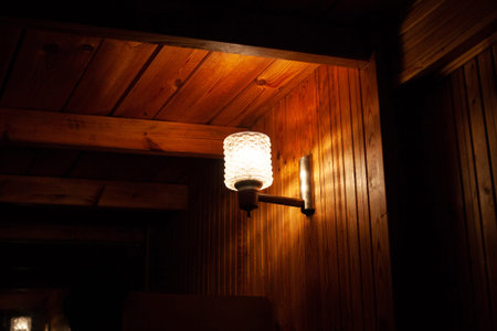 Vintage wall lamp. Interesting light on a wooden wall. Cozy room with soft light. Figured glass lampの写真素材