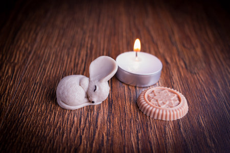 Photo decorative sleeping mouse figure with burning candle on wooden backgroundの写真素材
