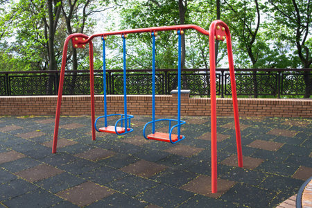 Two child swings in empty playground due coronavirus. Safety for children. Baby swings metal. Injury...
