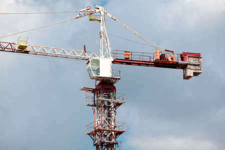 Construction cranes and building on construction site with cloudy blue sky background. Under construction. Growing city. Safety.の写真素材