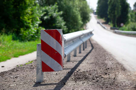 red road reflectors along the road. metal road fencing of barrier type, close-up. Road and traffic safety. reflective paint on sign. Median barrierの写真素材