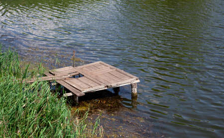 Old wooden pier on river. Bridge over calm water. Abandoned pier for fisherman. Fishing pond. Relaxの写真素材
