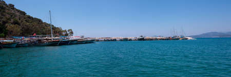 Many yachts and boats in the harbor. Ships on pier in port. Sea traveling. White pleasure yachts. Panoramic view. Kemer, Turkey - 07.07.の写真素材