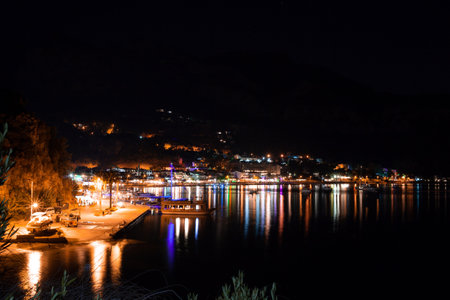 Night view of the embankment and promenade in the light of street lights and lighting of restaurants. small town surrounded by mountains in evening. Light reflections on sea water surface. cityscapeの写真素材