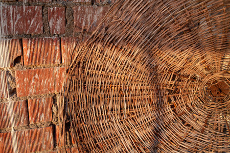 straw beach umbrella hat and red brick wall on a summer day, straw beach umbrella. end of tourist season.の写真素材
