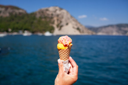 Ice cream cone held up to the hot summer sky. Female hand holding ice cream cone. Vanila ice creamの写真素材