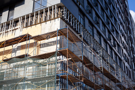 Extensive scaffolding providing platforms for work in progress on a new apartment block. Tall building under construction with scaffolds. Construction Site of New Buildingの写真素材