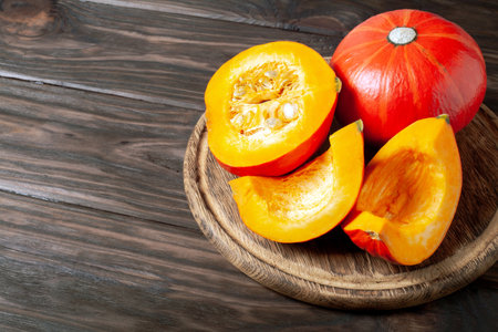 sliced pumpkin on dark wooden background. red pumpkin on table.の写真素材