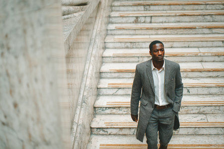 A man is vigorously running up a set of stairs in a vibrant city center. The sun shines brightly, highlighting the energetic atmosphere of the surroundings.の素材