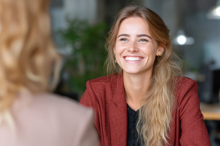 A manager is interviewing a candidate who is smiling and engaged, creating a friendly atmosphere in a minimal, modern office setting during the day.の素材
