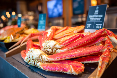 Uncooked crab claws and legs are arranged neatly on a wooden display at a seafood market. The vibrant colors highlight their freshness and appeal to customers.の素材