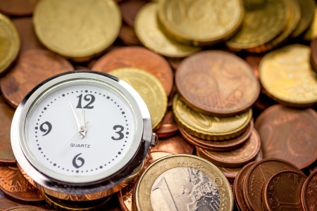 Euro coins and a clock showing 5 minutes until 12 の写真素材