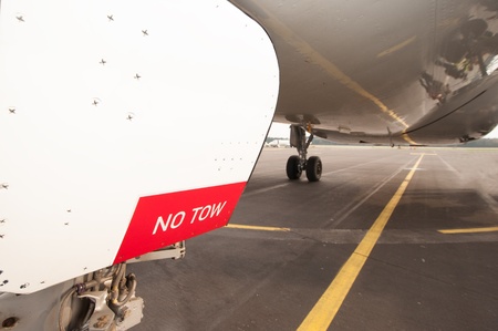 Sign NO TOW on undercarriage of airplane while waiting on runwayの写真素材