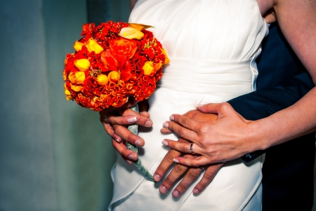 Wedding bouquet in bride's hand with groom's hands around herの写真素材