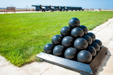 Old cannonballs stacked in pyramid, in front of blured cannons, on Valletta Castle, Maltaのeditorial素材