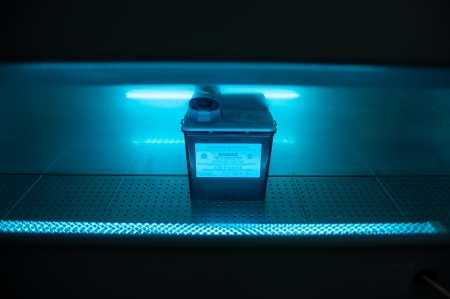 Box with danger virus content under ultravillet lightの写真素材