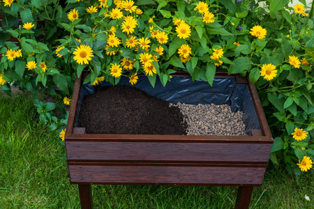 A wooden pot for growing vegetables or flowers. A layer of soil on the bottom a layer of expanded...