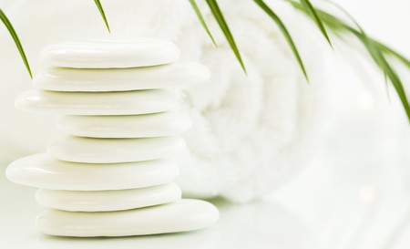 White pebbles, towel and palm leaf over white. Selective focus.の写真素材