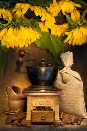 Stiill life with Antique coffee grinder, burlap sack, coffee cups, chocolate and  sunflowers on  rustic tableの写真素材