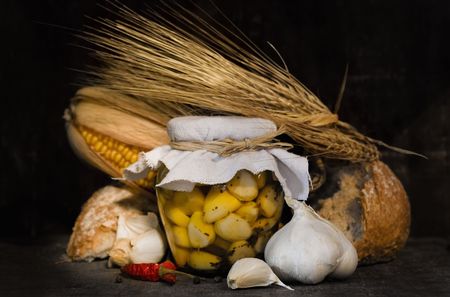 still life with marinated garlic, bread and cornの写真素材