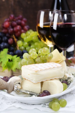 Grape and cheese with a bottle and glasses of red and white wineの写真素材
