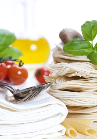 Italian Pasta with tomatoes, mushrooms, olive oil and basil on a white backgroundの写真素材