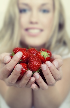 Beautiful young woman holding a lot of fresh strawberriesの写真素材