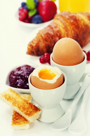 Delicious breakfast with eggs, fresh croissants, fructs and juiceの写真素材