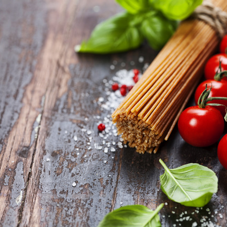 Spaghetti and tomatoes with herbs on an old and vintage wooden table の写真素材