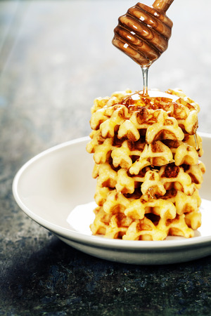 Waffles with honey on wooden tableの写真素材