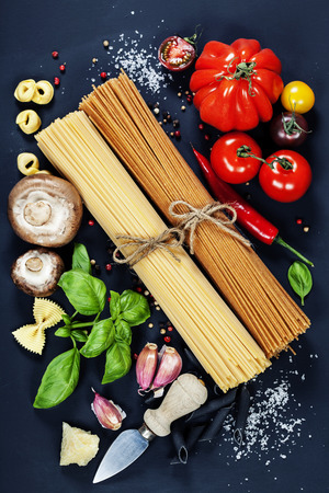 Italian ingredients - pasta, vegetables, spices, cheese - on dark backgroundの写真素材