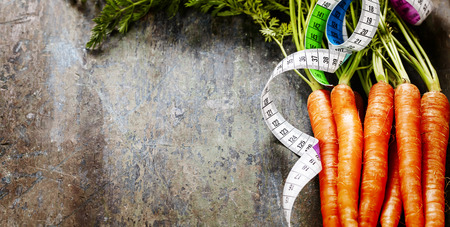 fresh carrots bunch and measurement tape - diet and healthy eating conceptの写真素材