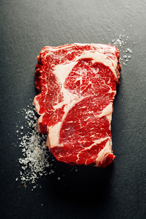 Raw beef steak on a dark slate backgroundの写真素材