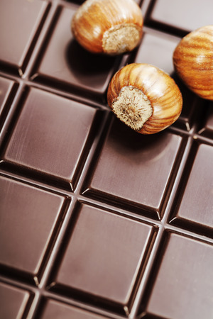 dark chocolate bar with hazelnuts as backgroundの写真素材
